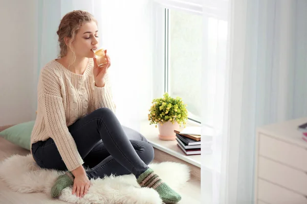 Młoda kobieta w pobliżu okna w domu do picia herbata biała — Zdjęcie stockowe