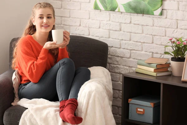 Giovane donna a riposo con una tazza di tè in poltrona a casa — Foto Stock