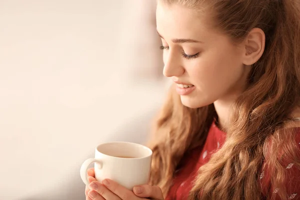 Молода жінка п'є чай на розмитому фоні — стокове фото