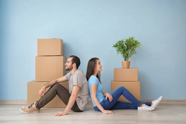 Young couple resting near boxes indoors. Moving into new house — Stock Photo, Image