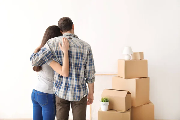Young couple hugging near boxes indoors. Moving into new house — Stock Photo, Image