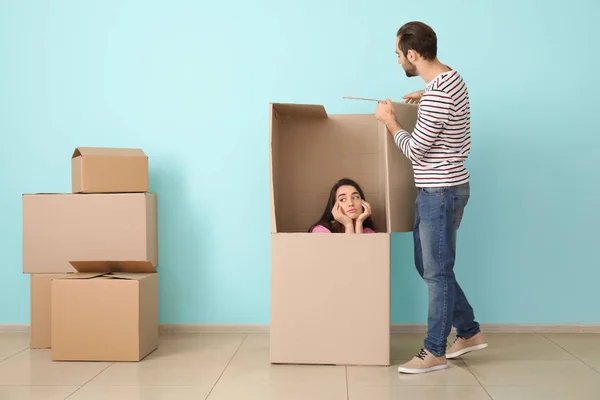 Pareja joven jugando con una caja enorme en el interior. Mudándose a casa nueva —  Fotos de Stock