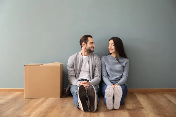 Молода пара сидить на підлозі біля коробки в приміщенні. Переїзд у новий будинок — стокове фото