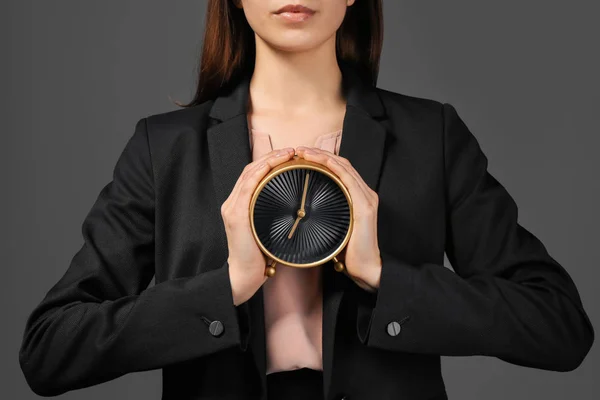 Frau hält Uhr auf dunklem Hintergrund. Zeitmanagement-Konzept — Stockfoto
