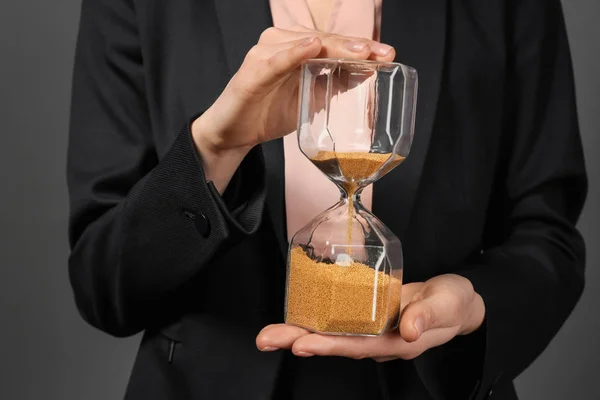 Woman holding hourglass on dark background. Time management concept — Stock Photo, Image