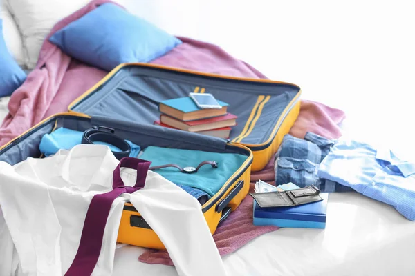 Open travel suitcase with clothes on bed — Stock Photo, Image