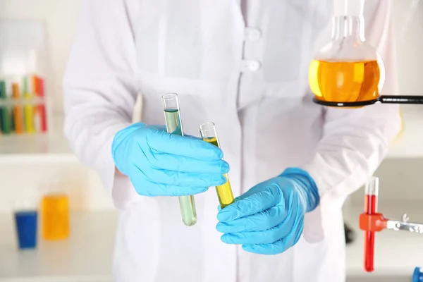 Assistente de laboratório segurando tubos de ensaio com líquidos coloridos, close-up — Fotografia de Stock