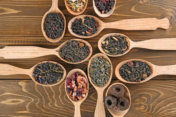 Verschillende soorten thee in lepels op houten achtergrond, plat leggen — Stockfoto