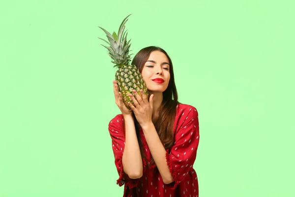 Aantrekkelijke jonge vrouw met ananas op kleur achtergrond — Stockfoto