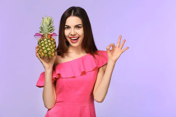 Attractive young woman holding pineapple with sunglasses on color background — Stock Photo, Image