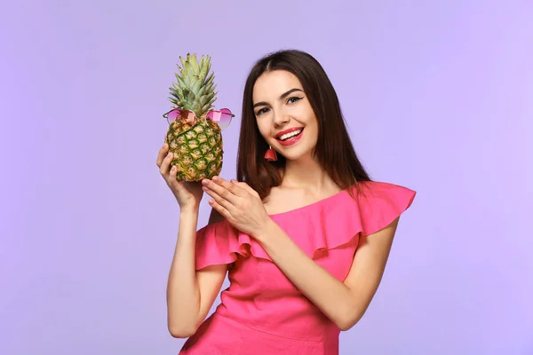 Attractive young woman holding pineapple with sunglasses on color background — Stock Photo, Image