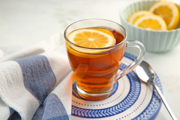 Glass cup of aromatic tea with lemon on plate — Stock Photo, Image