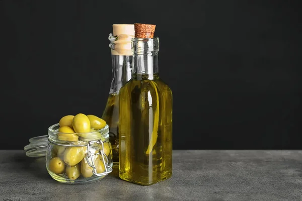 Bottles with olive oil on table against dark background — Stock Photo, Image