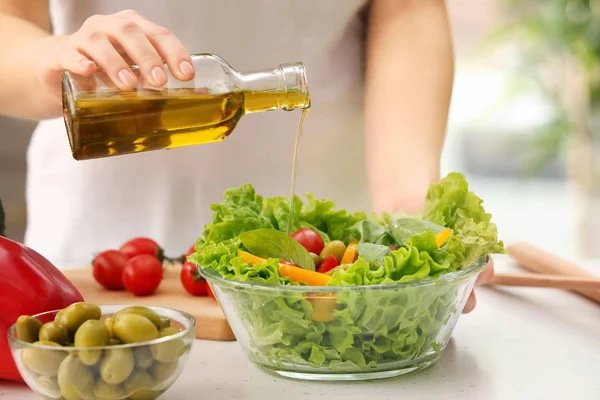 Vrouw dressing verse fruit salade met olijfolie in keuken — Stockfoto