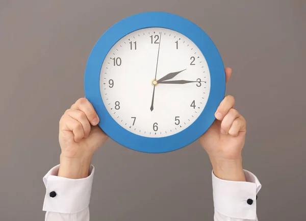Man håller klockan på grå bakgrund. Time management koncept — Stockfoto