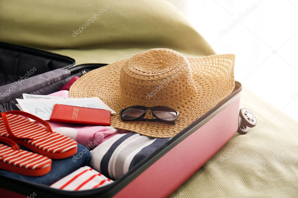 Open suitcase with packed things on bed