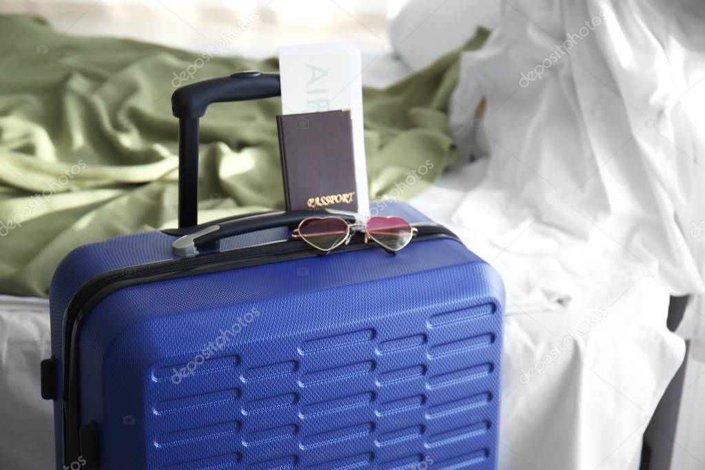 Sunglasses and documents on travel suitcase indoors