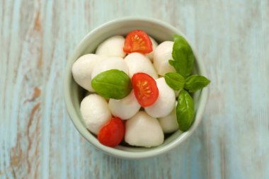 Mozzarella peynir topları, domates ve fesleğen ahşap arka plan üzerinde kase