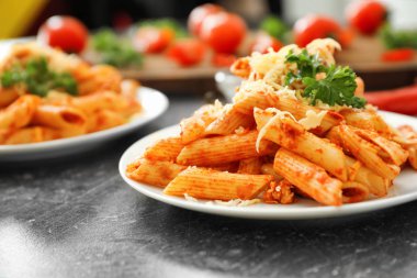Lezzetli penne makarna ve gri masada rendelenmiş peynir ile plaka