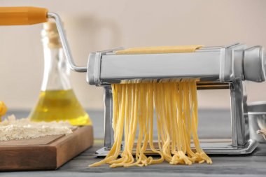 Mutfak masasının üzerinde hamur ile metal makarna üreticisi