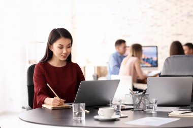 Ofiste iş toplantısı için hazır olmak için dizüstü bilgisayar kullanan genç kadın