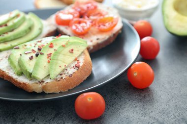 Plaka üzerinde avokado ve kiraz domatesli ekmek