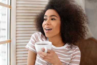 Güzel bir Afrikalı-Amerikalı kadın pencere çay içme