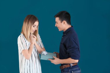 Renk arka plan üzerinde sevgili kız arkadaşına hediye veren genç adam