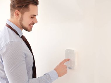 Genç adam güvenlik alarm sistemi üzerinde kapalı kodunu girme