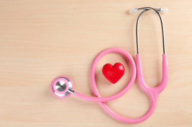 Ahşap arka plan üzerinde küçük kalbi steteskop