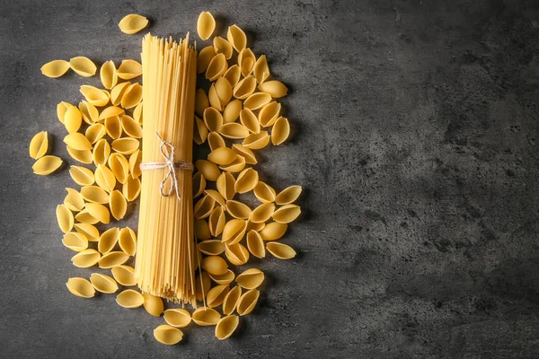 Different uncooked pasta on grey background