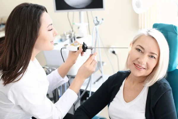 Otolaryngologist examining woman's ear with ENT telescope in hospital — Stock Photo, Image