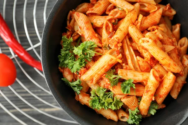 Sartén con sabrosa pasta de penne y salsa de tomate en el estante de enfriamiento, primer plano — Foto de Stock