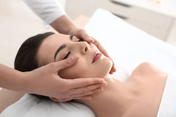 Mujer joven disfrutando de masajes faciales en el salón de spa —  Fotos de Stock