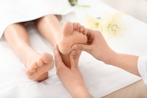 Young woman enjoying foot massage in spa salon, focus on legs
