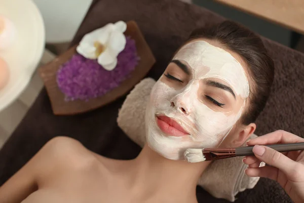 Косметолог надевает маску на лицо молодой женщины в салон красоты — стоковое фото
