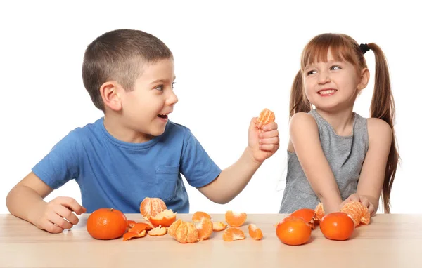 Aranyos kis gyerekek citrusfélék asztalnál eszik a fehér háttér — Stock Fotó