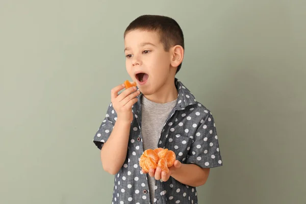 Divertente piccolo ragazzo mangiare agrumi su sfondo di colore — Foto Stock