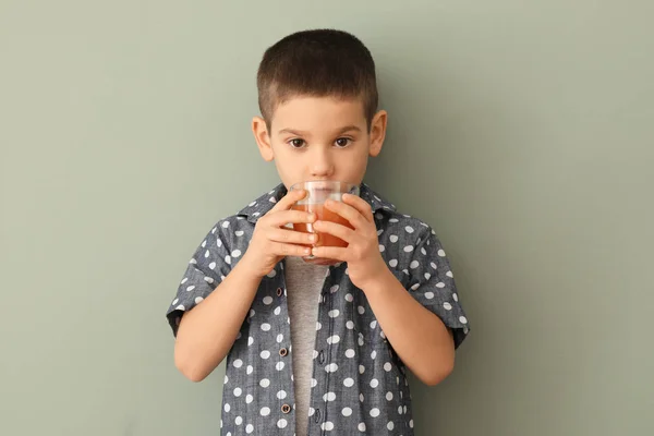 Funny little boy drinking citrus juice on color background — Stock Photo, Image