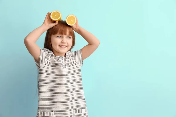 Funny little girl with citrus fruit on color background — Stock Photo, Image