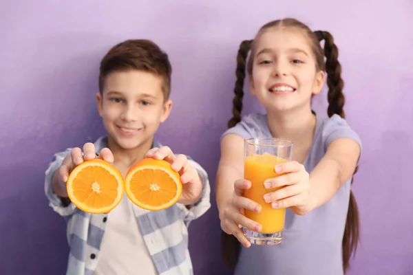 Crianças engraçadas com frutas cítricas e suco no fundo de cor — Fotografia de Stock