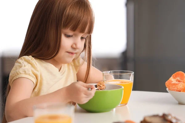 Vicces kislány reggelizik és fogyasztása citrus gyümölcslé otthon — Stock Fotó