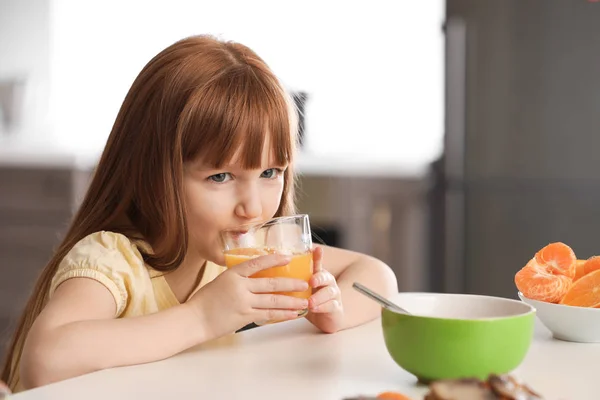 Funny little girl drinking citrus juice at home — Stock Photo, Image