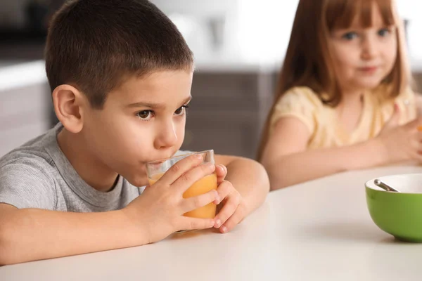 Funny little children drinking citrus juice at home — Stock Photo, Image