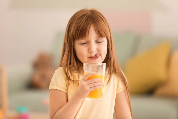 Graciosa niña bebiendo jugo de cítricos en casa — Foto de Stock