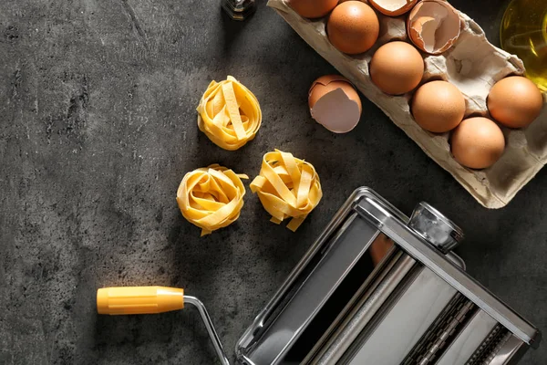Metal pasta maker and products on kitchen table, top view — Stock Photo, Image