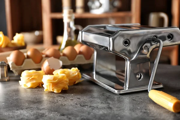 Fém tészta készítő és termékek a konyhaasztalon — Stock Fotó