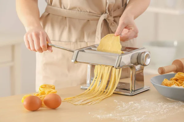 Woman making noodles with pasta machine at table — Stock Photo, Image