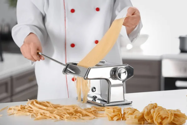 Vrouwelijke chef-kok noedels met Pastamachine aan tafel maken — Stockfoto