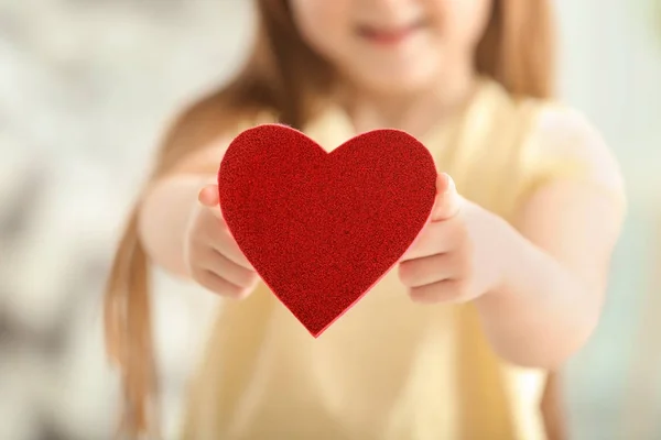 可爱的小女孩与红色心脏在模糊的背景, 特写 — 图库照片